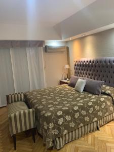 a bedroom with a large bed and a chair at Tagle-Recoleta in Buenos Aires