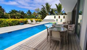 um pátio com uma mesa e cadeiras ao lado de uma piscina em Mama Taras Luxury Villa em Ngatangiia