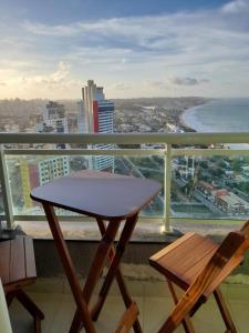 a table and two chairs on a balcony with a view of the ocean at Ponta Negra RN01 in Natal