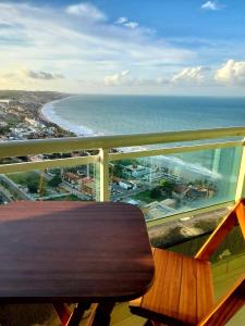 un banco de madera sentado en un balcón con vistas al océano en Ponta Negra RN01, en Natal
