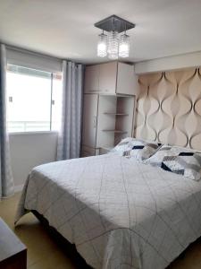 a bedroom with a large bed and a chandelier at Ponta Negra RN01 in Natal
