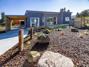 a house with rocks in front of a yard at Family Retreat in Snowmass - Ohakune Holiday Home in Ohakune