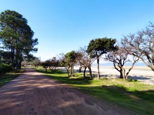 a dirt road with trees on the side of a beach at GUSMAR - Hermosa y confortable casa a pasos de la playa. in Santa Ana