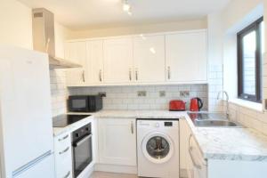 a white kitchen with a washing machine and a sink at The Osprey - Newly Renovated House in Castle Gresley