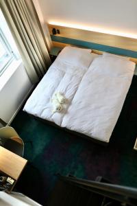 a white dog laying on a bed in a room at Hotel Aurora in Nuuk