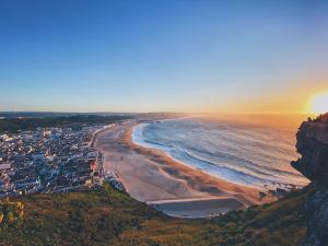 an aerial view of a beach at sunset at BrightHouse - Modern Apartments in Sítio Nazaré in Nazaré