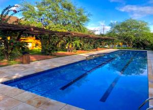 a swimming pool with blue water in front of a house at Gravata Apartamento Winterville in Gravatá