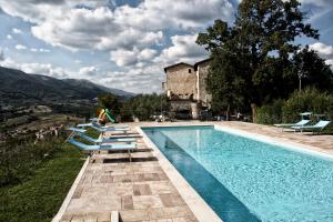 a swimming pool with lounge chairs and a house at Il Castello Di Perchia in Crocemaroggia