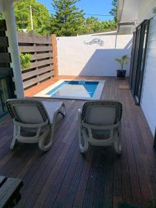 two chairs sitting on a deck next to a swimming pool at Kaia Villas in Rarotonga