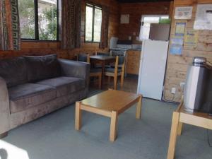 un soggiorno con divano, tavolo e frigorifero di Ossies Motels and Chalets a Ohakune