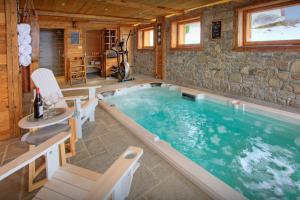 a large swimming pool in a room with a stone wall at La Ferme du Gran Shan - OVO Network in Les Villards-sur-Thônes