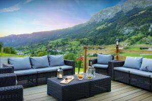 a patio with wicker furniture and a view of a mountain at La Ferme du Gran Shan - OVO Network in Les Villards-sur-Thônes