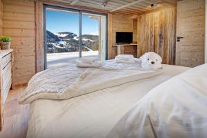 a white dog laying on a bed in a room with a window at Chalet Charmar - OVO Network in La Clusaz