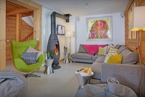 a living room with a gray couch and a green chair at Chalet Le Mousqueton - OVO Network in La Clusaz