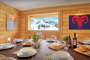 a dining room with a table with food and wine bottles at Chalet Le Mousqueton - OVO Network in La Clusaz