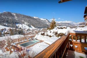 a snow covered balcony with a swimming pool on a mountain at Chalet Le Mousqueton - OVO Network in La Clusaz