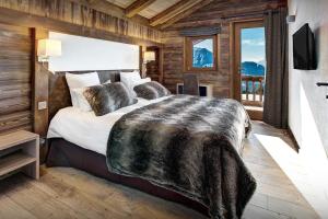 a bedroom with a large bed in a room with wooden walls at Pralor Le Nova - OVO Network in Manigod