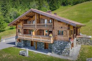 ein großes Holzhaus mit einem großen Balkon auf einem Hügel in der Unterkunft Pralor Le Nova - OVO Network in Manigod