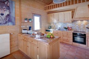 a kitchen with wooden cabinets and a table with fruit on it at Chalet des Mômes - OVO Network in Le Grand-Bornand