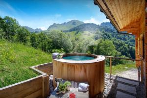a hot tub on a deck with a view of mountains at Chalet des Mômes - OVO Network in Le Grand-Bornand