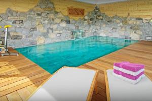 una grande piscina con parete in pietra di Lodge La Source - OVO Network a Les Clefs