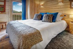 een slaapkamer met een groot bed met blauwe kussens bij Chalet de Paul et Marie - OVO Network in Manigod