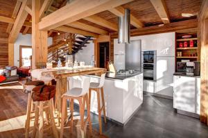 een keuken met houten plafonds en een bar met krukken bij Chalet Alti - OVO Network in Le Grand-Bornand