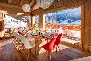 a dining room with a table and chairs and a large window at Chalet Alti - OVO Network in Le Grand-Bornand