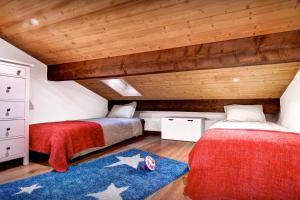 two beds in a room with wooden ceilings at Chalet La Frasse - OVO Network in La Clusaz