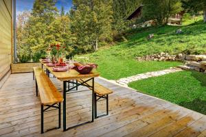 a wooden deck with a table and benches on it at Chalet La Frasse - OVO Network in La Clusaz