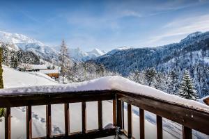 a snow covered balcony with a view of mountains at Chalet Les Houlottes - OVO Network in Manigod