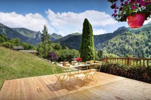 a patio with a table and chairs and mountains at Chalet Les Houlottes - OVO Network in Manigod