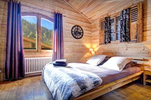 a bedroom with a bed in a wooden room at Chalet Le Petit Mazot - OVO Network in La Clusaz