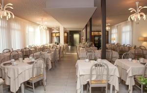 a dining room with white tables and chairs at Hotel Helvetia in Lido di Jesolo