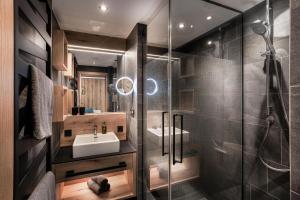 uma casa de banho com um lavatório e uma cabina de duche em vidro. em Apartments Niederseer em Saalbach Hinterglemm