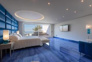 a bedroom with blue floors and a bed with a large window at Grotta Palazzese Beach Hotel in Polignano a Mare