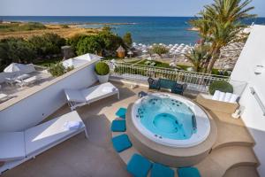 bañera de hidromasaje en un balcón con vistas al océano en el fondo en Grotta Palazzese Beach Hotel, en Polignano a Mare
