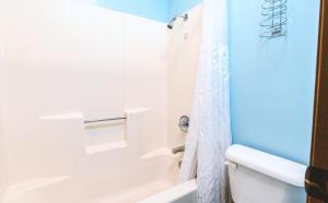 a bathroom with a white tub and a white shower curtain at Blue Way Inn & Suites Wellington in Wellington