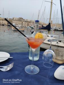 a drink in a glass on a table next to a bottle at Semi-basement, cosy apartment interconnected to our residence a traditional Maltese townhouse in Senglea