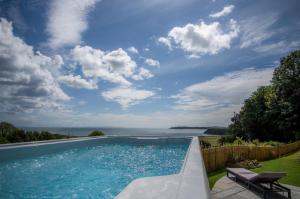 a swimming pool with a view of the ocean at Penally Manor - Luxurious Manor House - Tenby in Penally