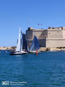 two sailboats in the water in front of a building at Semi-basement, cosy apartment interconnected to our residence a traditional Maltese townhouse in Senglea