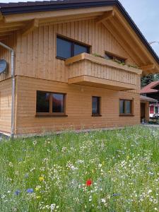 una casa con un campo de flores delante de ella en Ferienwohnung Fernweh en Bolsterlang