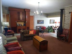 een woonkamer met een bank, stoelen en een tafel bij Fisant, Bokmakierie and Hoephoep Guest House in Bethlehem