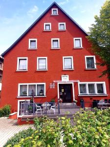 un bâtiment rouge avec des tables et des chaises devant lui dans l'établissement Hotel Luca, à Betzenstein