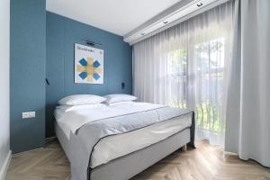 sypialnia z łóżkiem z niebieskimi ścianami i oknem w obiekcie City Apartments - Apartamenty Butikowe w Koszalinie