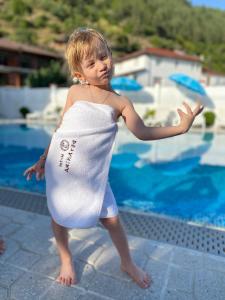 a young girl wearing a towel around her waist near a swimming pool at Hotel Deyanira in Gorno Dryanovo