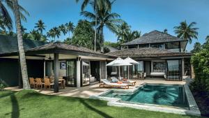 
a patio area with a pool, chairs, and a patio umbrella at Nikki Beach Resort & Spa Koh Samui - SHA Extra Plus in Lipa Noi
