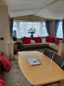 a living room with a table and a couch at Serendipity Caravan Hire in Chapel Saint Leonards