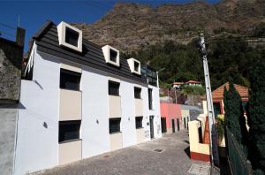 um edifício branco e preto com uma montanha ao fundo em Coração da Madeira em Curral das Freiras