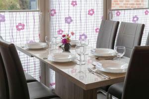 une table avec des assiettes et des verres à vin dessus dans l'établissement Ferienhaus-Lucky-bis-6-Personen-mit-Garten-und-Haustier, à Norddeich